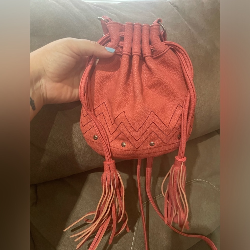 Coral colored bag, cinches at the top for closure, zipper inside